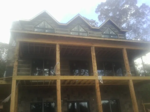 Dormers and porch framing on a large log home under construction — Roof Coating work by our crew in Underhill