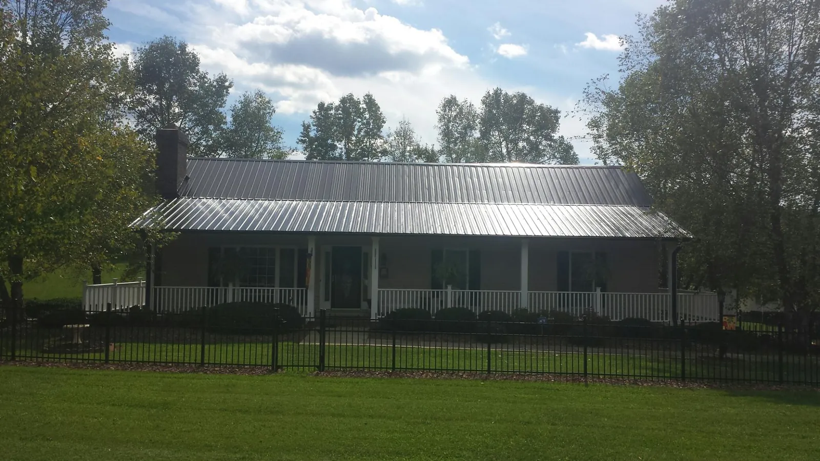 Gray metal roof on a brick ranch with a full width front porch — Gutter Guard Installation work by our crew in Underhill