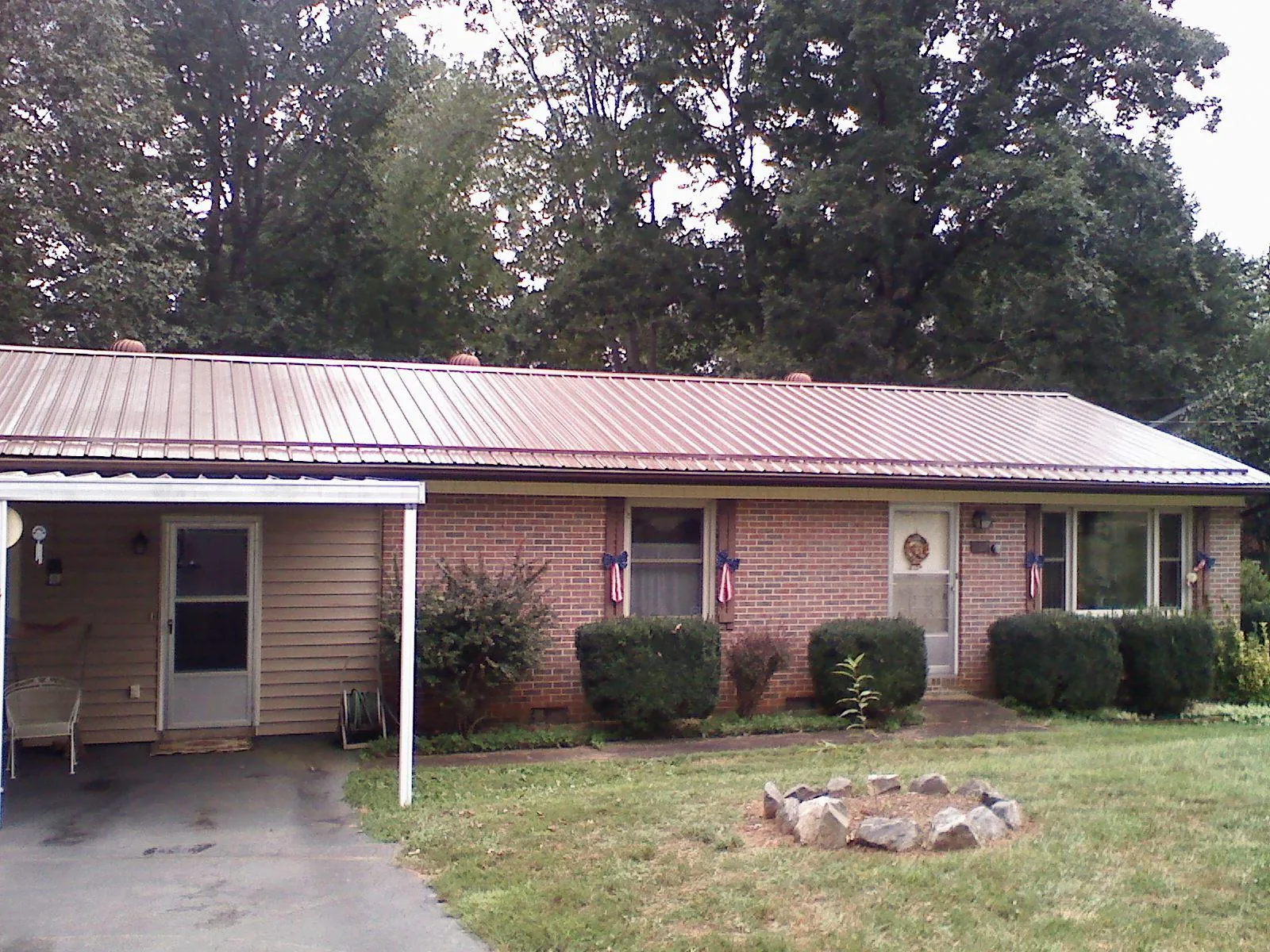 Bronze metal roof and carport on a brick ranch home — Roof Repair work by our crew in Underhill