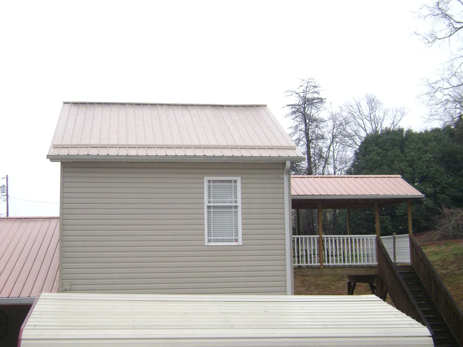 Tan metal roofs on a two story addition and attached porch, from a Roof Replacement job in Underhill